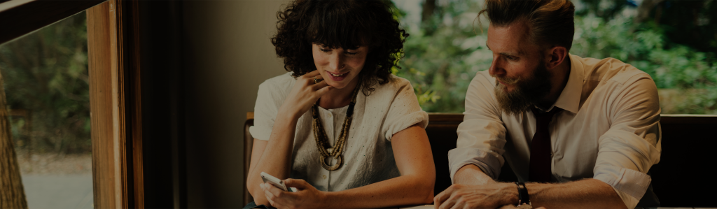 a man and a woman sitting at a table looking at the woman's phone